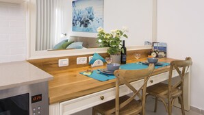 A modern kitchen with a wooden countertop, white cabinetry, a built-in microwave, and a large mirror above the sink. - HaBaitBe Matityahu (Beersheba)