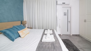 A hotel room with a bed, a nightstand, a lamp, a door, and a wardrobe. - HaBaitBe Matityahu (Beersheba)