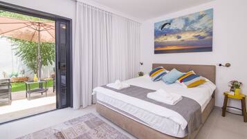 Un dormitorio con cama, un cuadro, una ventana con cortinas y vistas al exterior.