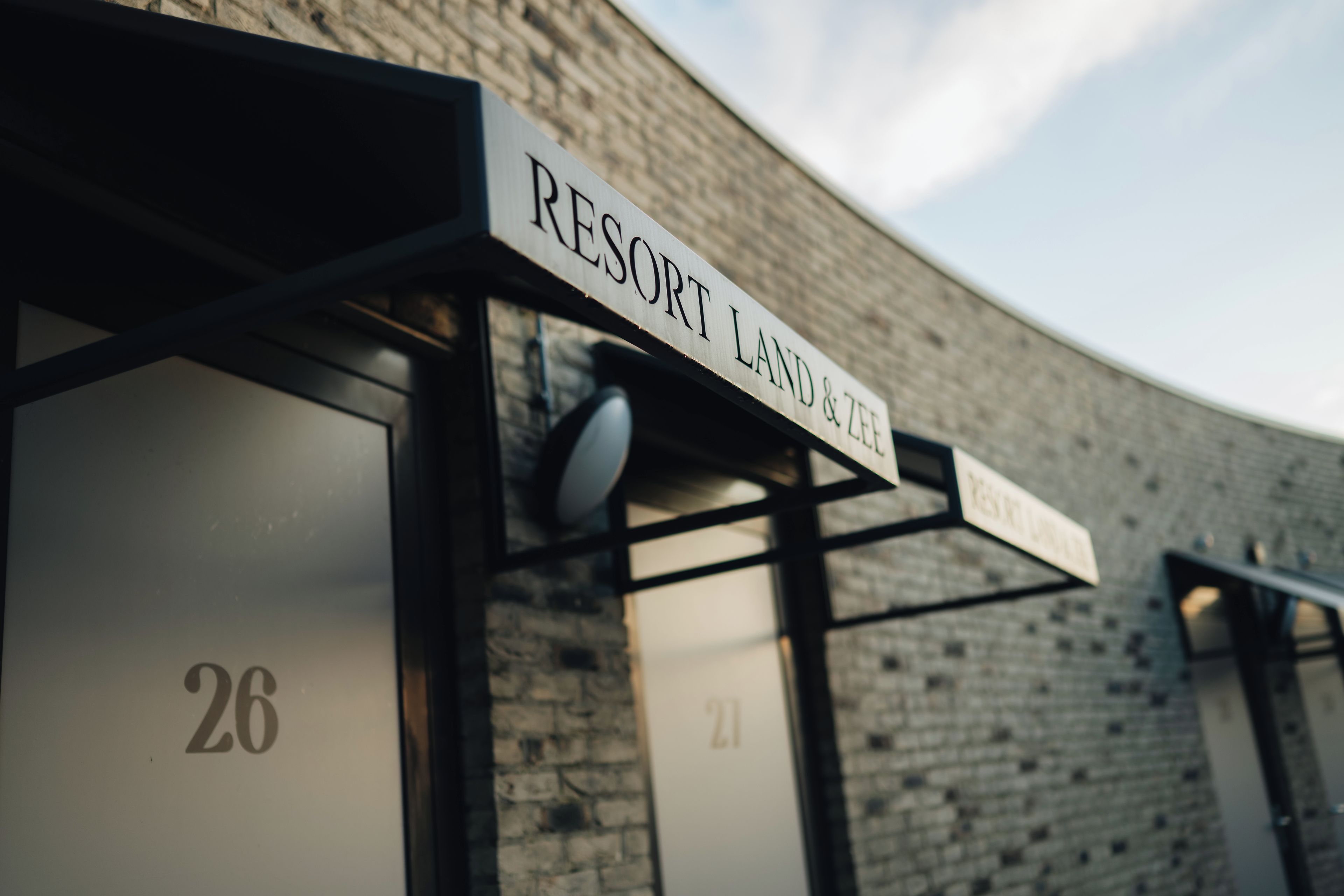 Un edificio con un letrero que dice 'RESORT LAND & ZEE' y puertas numeradas 21 y 26.