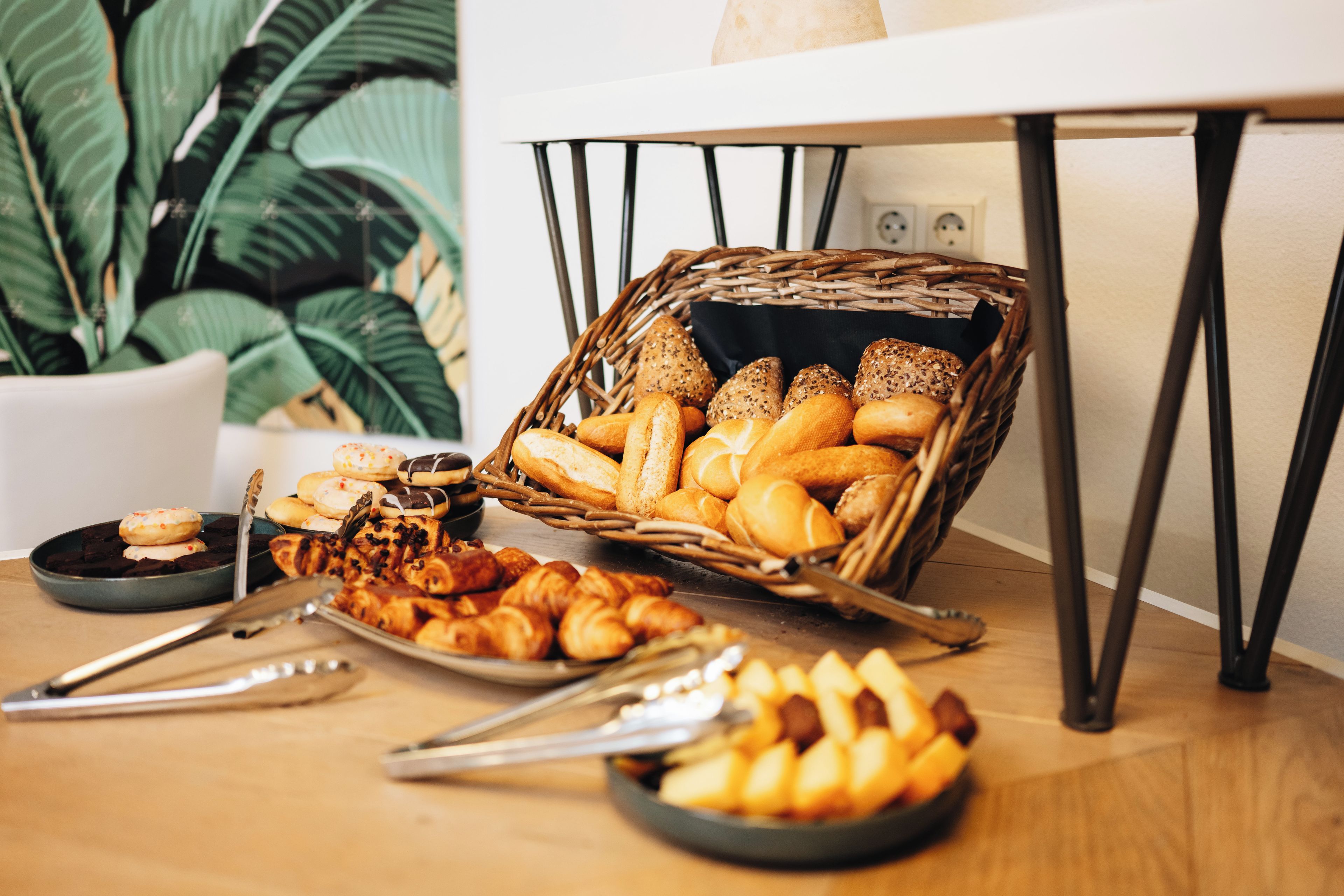 Une table garnie d’une variété de produits de boulangerie, notamment du pain et des viennoiseries, ainsi qu’un panier en osier rempli d’autres pains.
