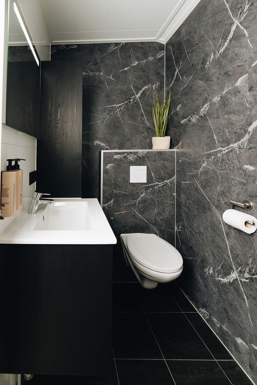 Une salle de bain moderne avec une baignoire blanche, des toilettes et un mur en marbre.