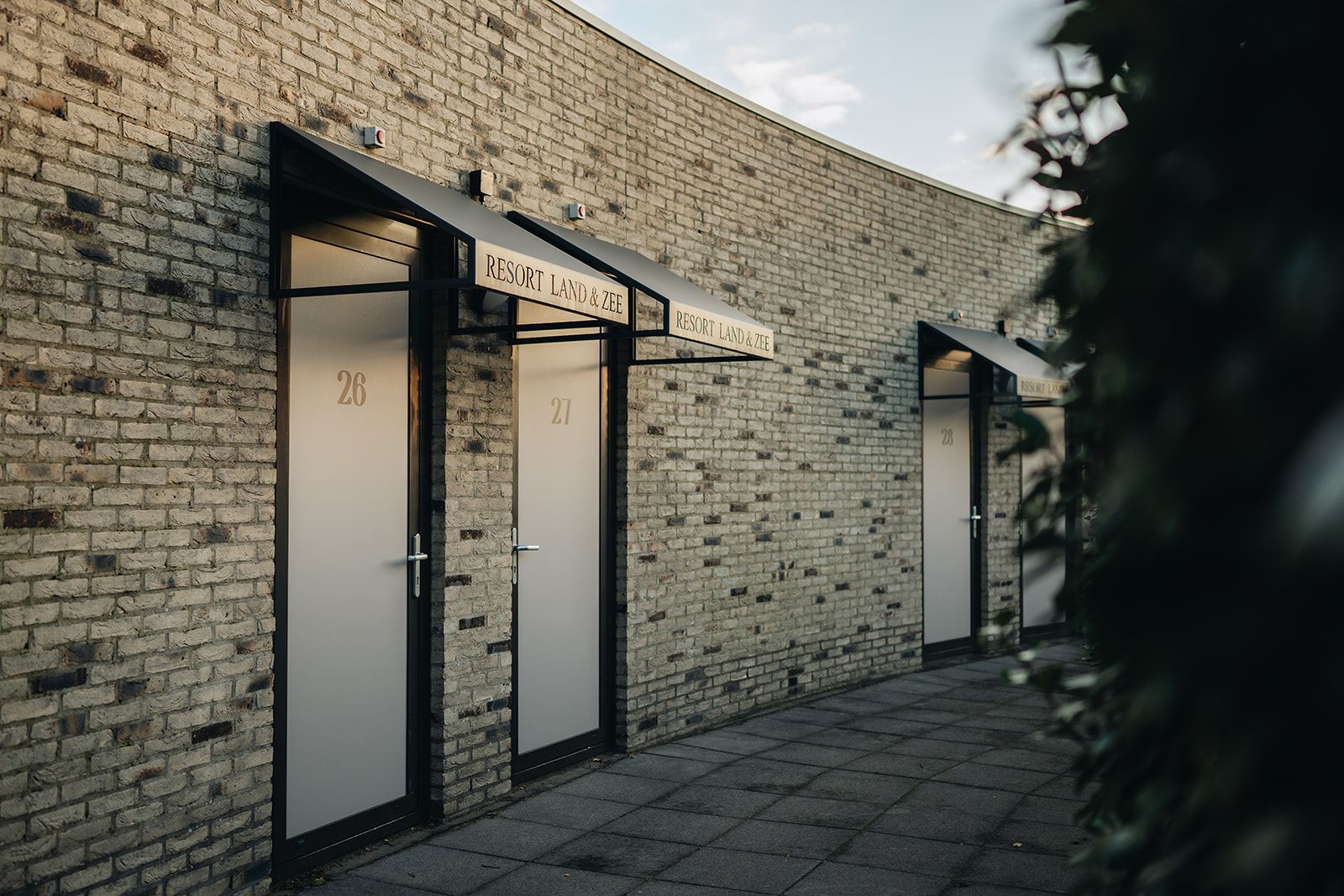 A building with numbered doors, each labeled 'RESORT LAND & ZEE,' suggesting a hotel or resort.