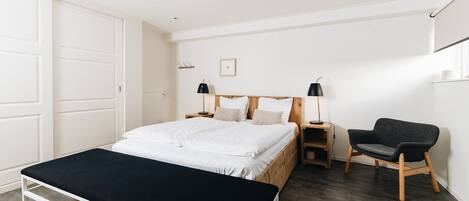 A bedroom with a bed, bedside tables, a chair, and a bench.