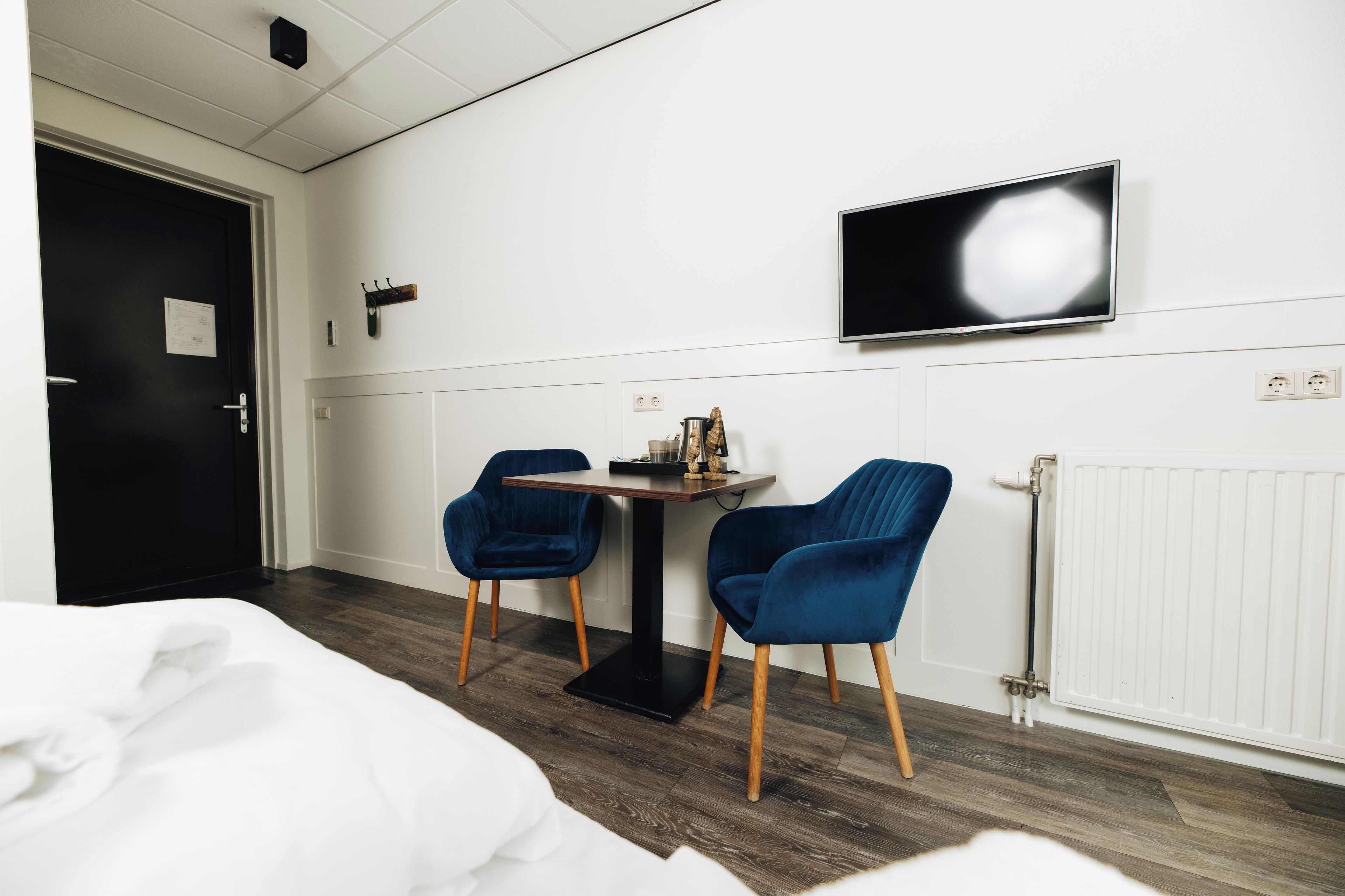 Ein Hotelzimmer mit Bett, Schreibtisch, zwei Stühlen, Fernseher und Heizkörper.