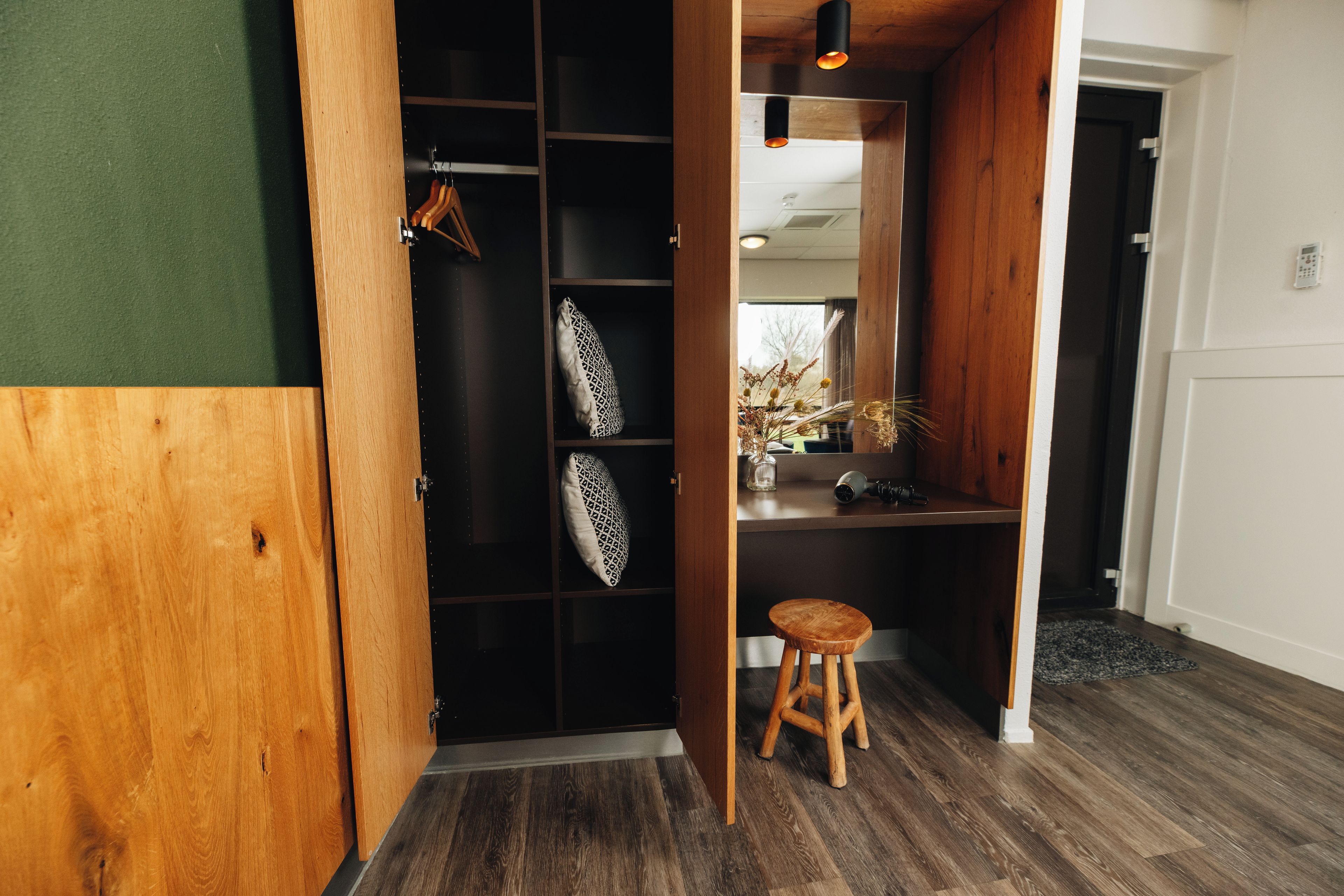 Un interior de madera con un banco, una estantería con cojines estampados y un perchero colgado.