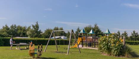 A playground with swings, a slide, and a playhouse.