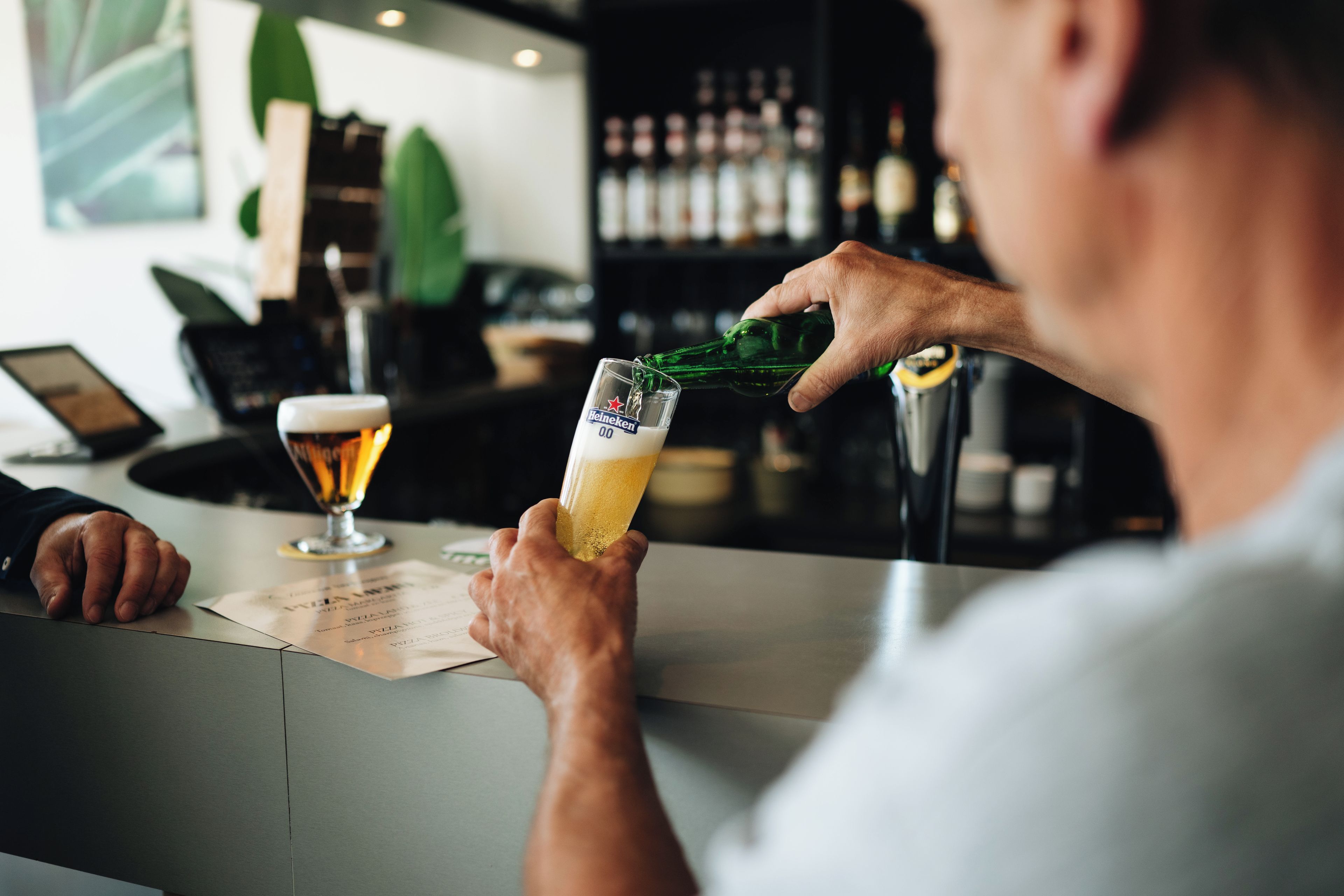 Iemand giet een drankje in een glas bij een bar.