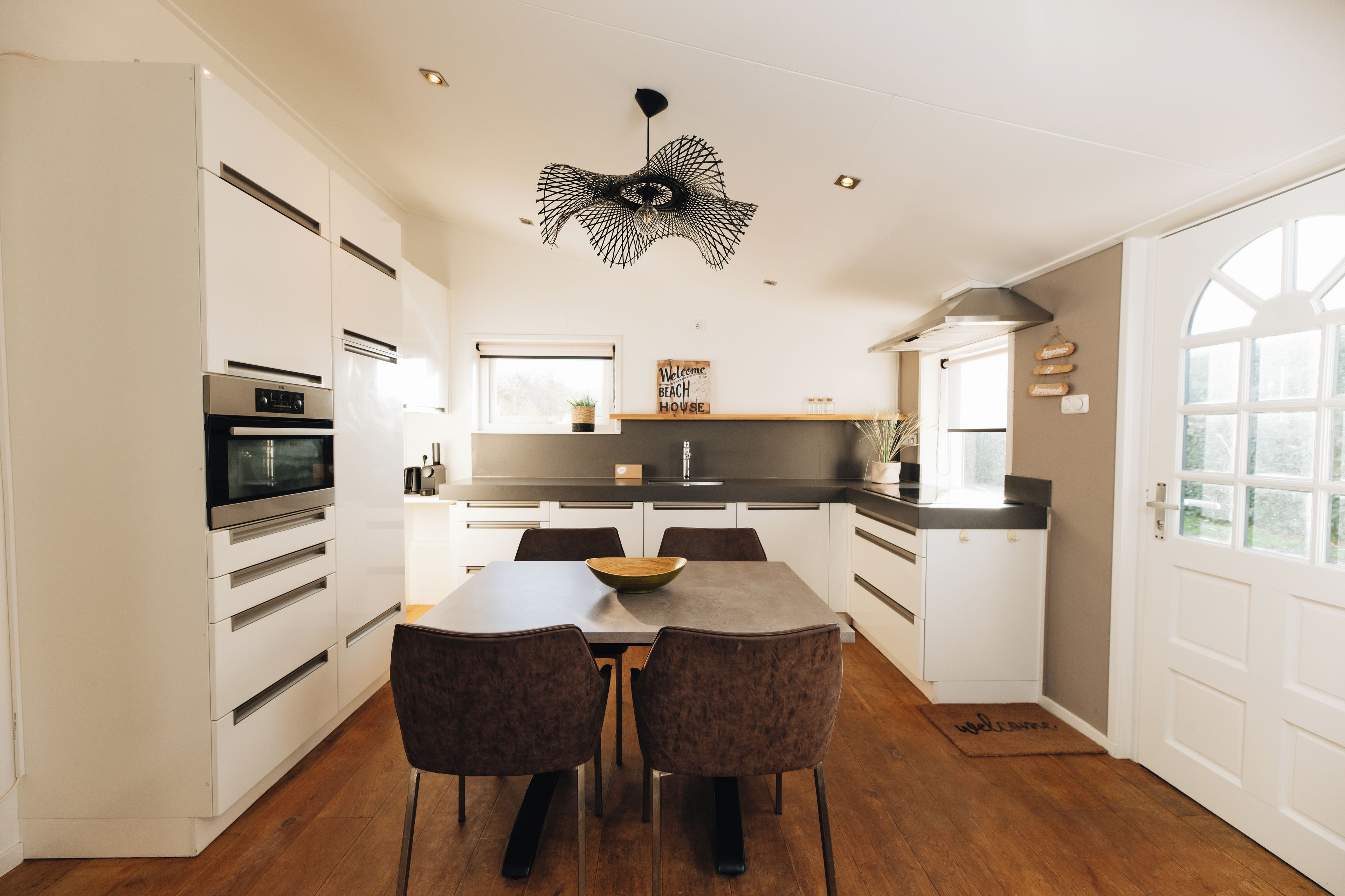 A modern kitchen with white cabinetry, a central island, and a dining area with two chairs.