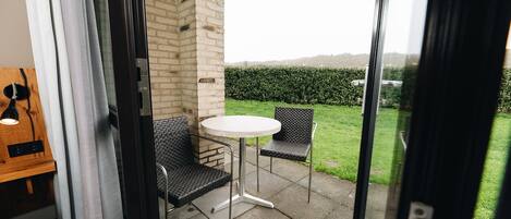 A glass door leading to an outdoor patio with a round table and two chairs.