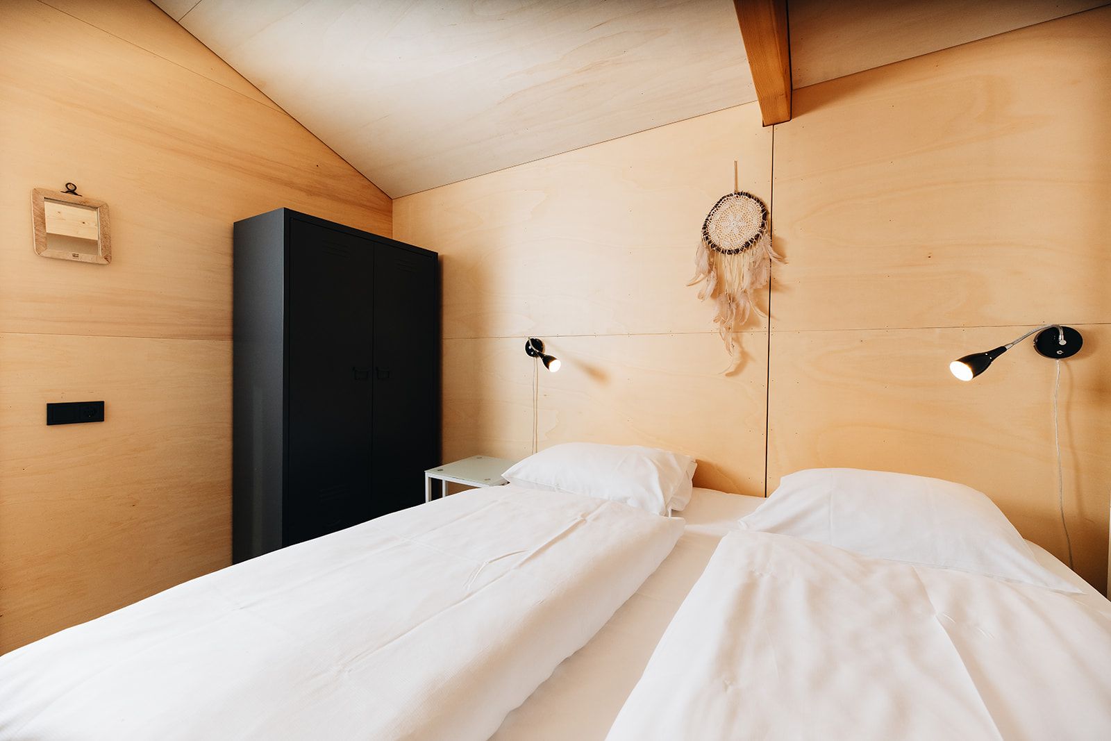 A bedroom with a bed, bedside tables, a wardrobe, and a dreamcatcher.