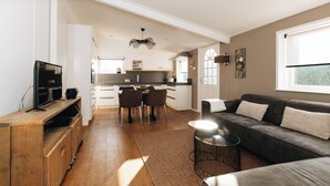 A modern kitchen with a dining area, a sofa, and a TV. - Resort Land en Zee (Noordwelle)