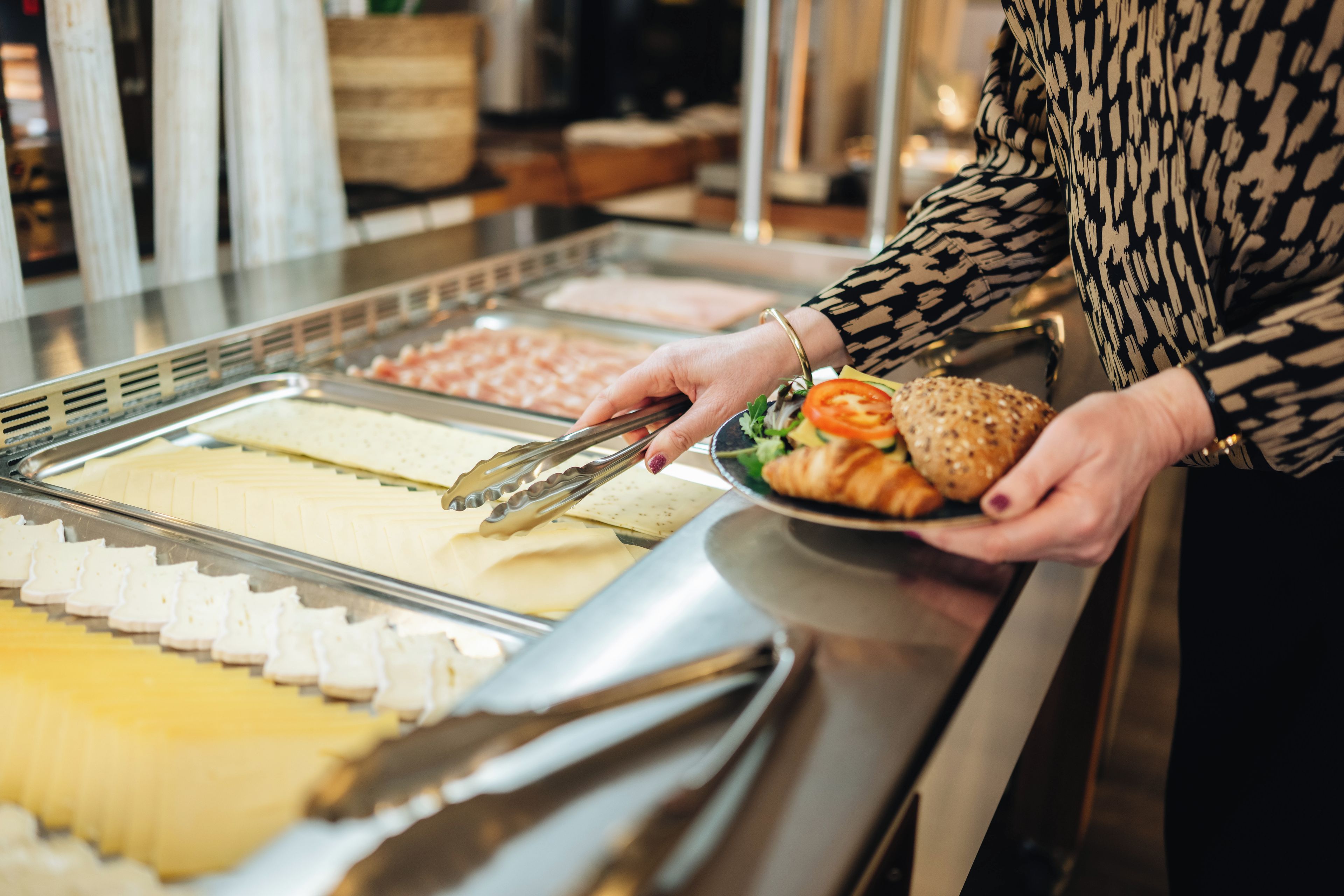 A buffet with various food items and a person serving themselves.