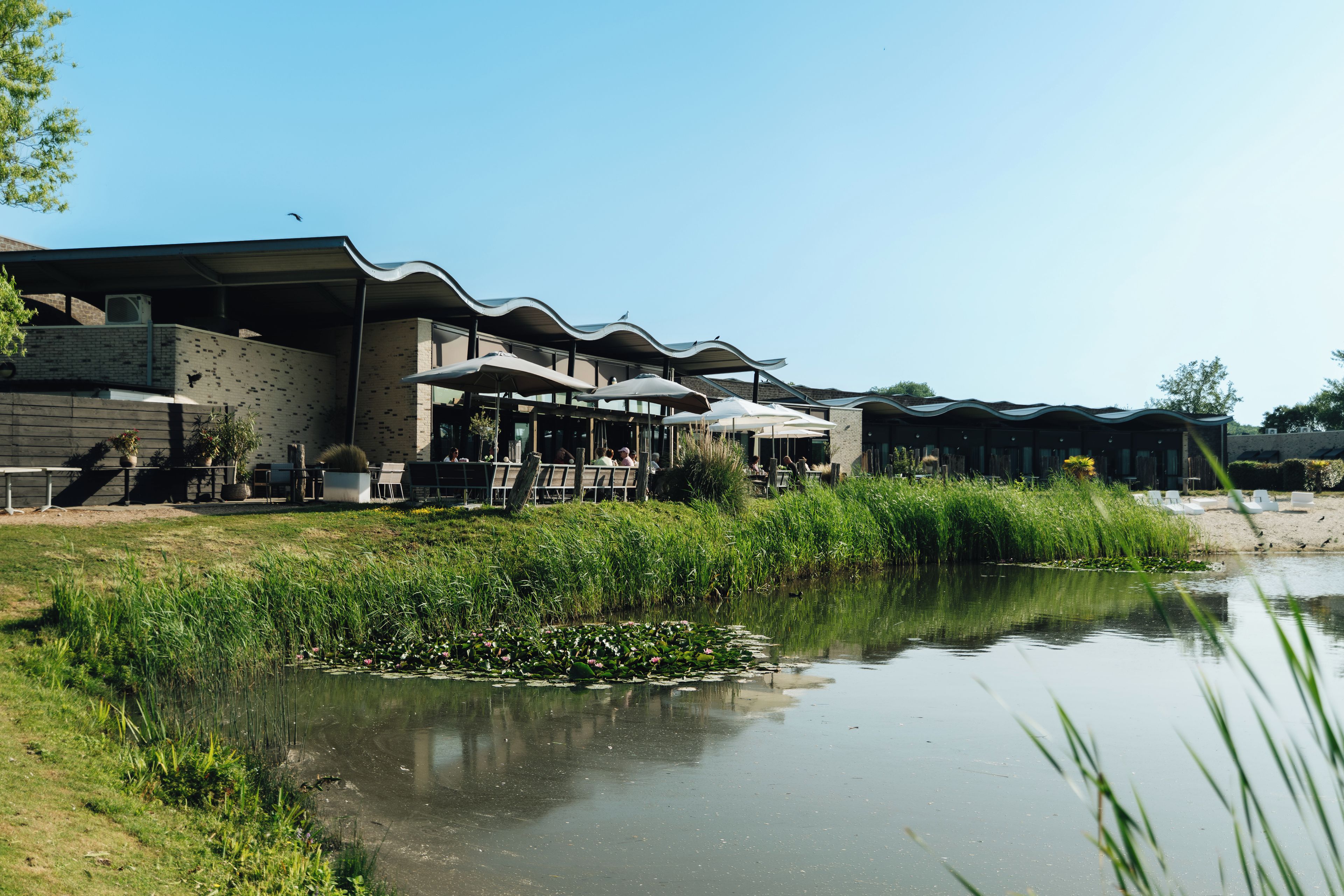 Un edificio sul fiume con posti a sedere all'aperto e uno stagno.