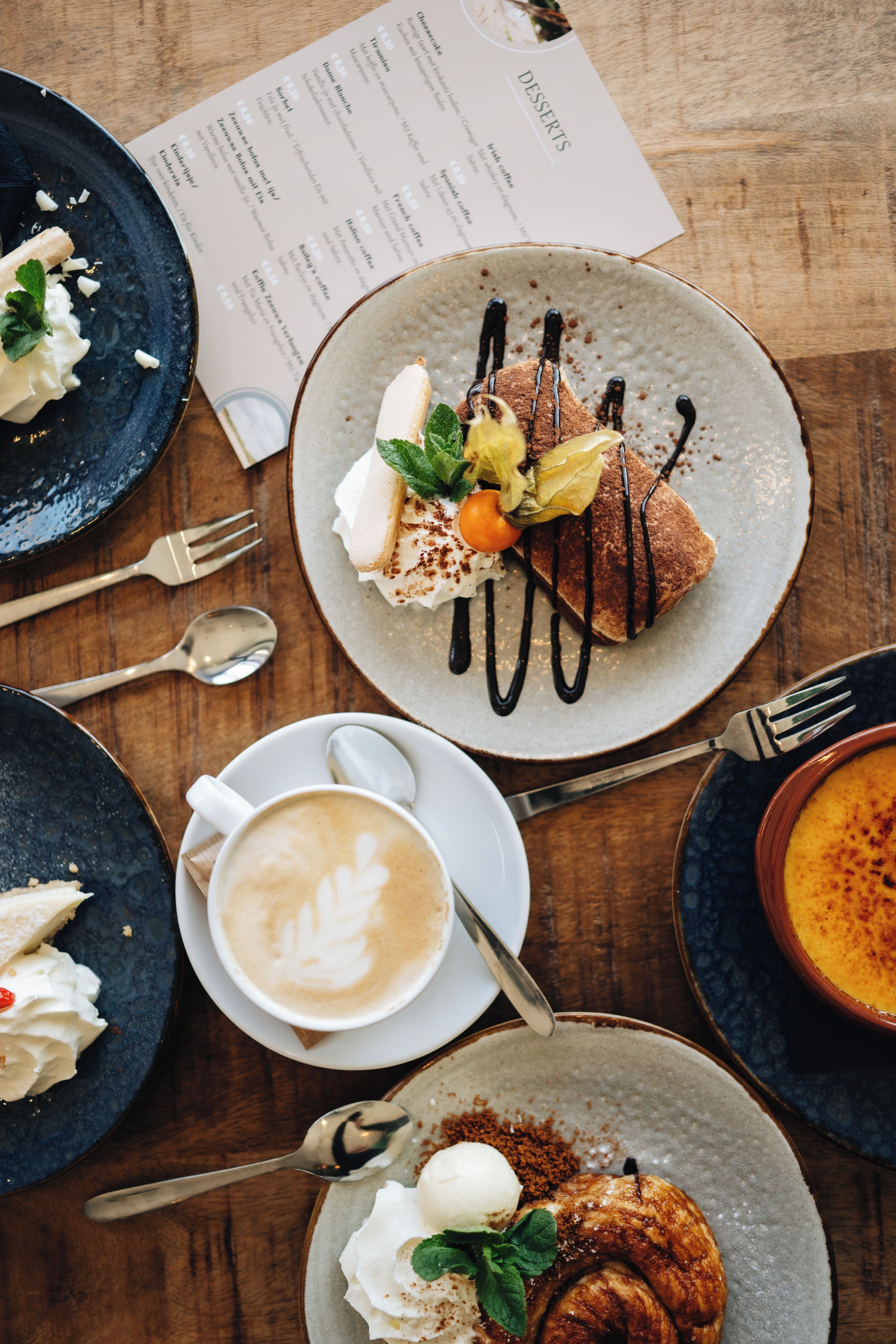 A table with a dessert plate, a coffee cup, and a menu.