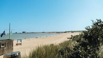 Ein Strand mit einer Holzzaun, einer Bank und blauem Himmel.