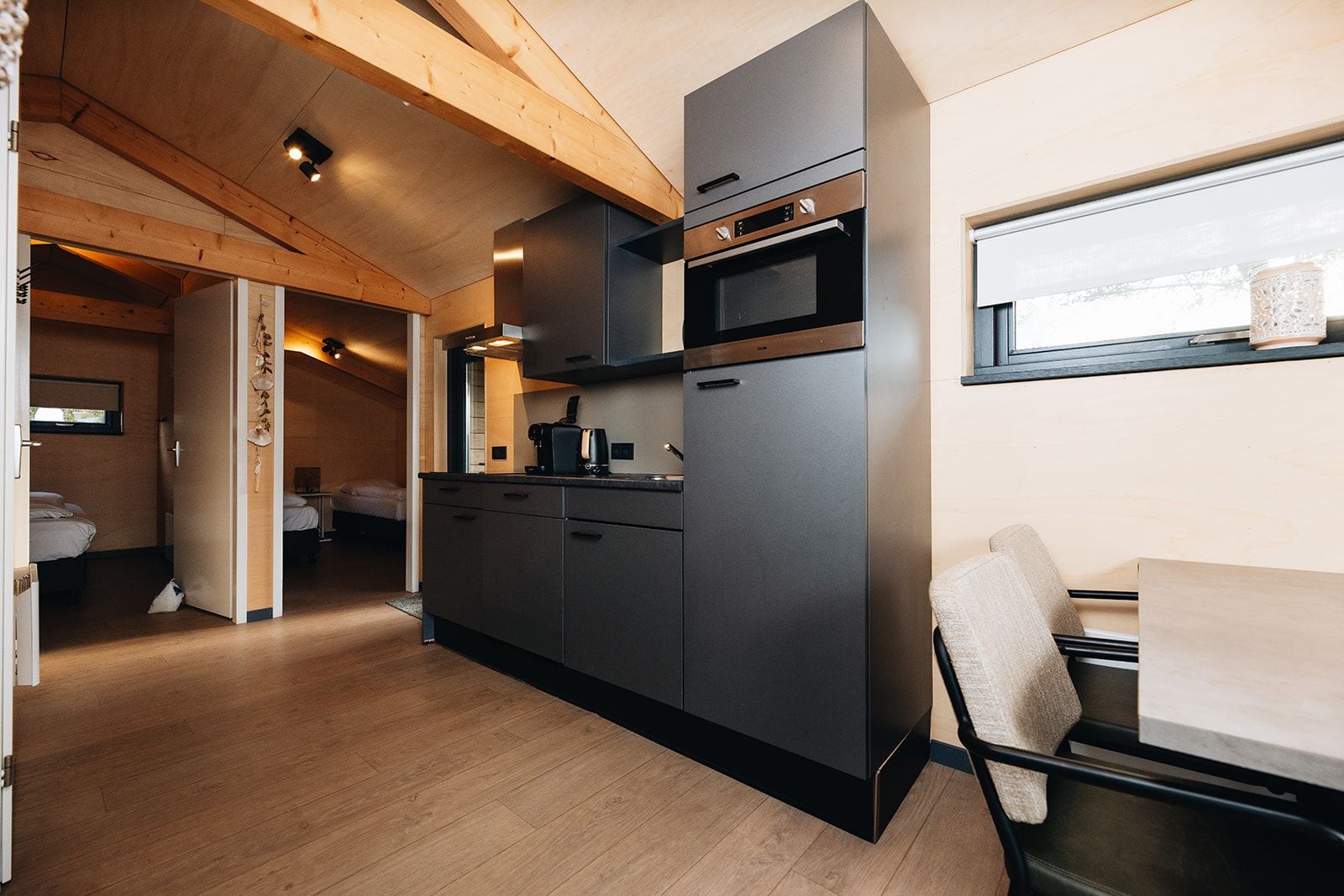Una cucina compatta con forno a incasso, microonde e un piccolo angolo ristoro con tavolo e sedia.