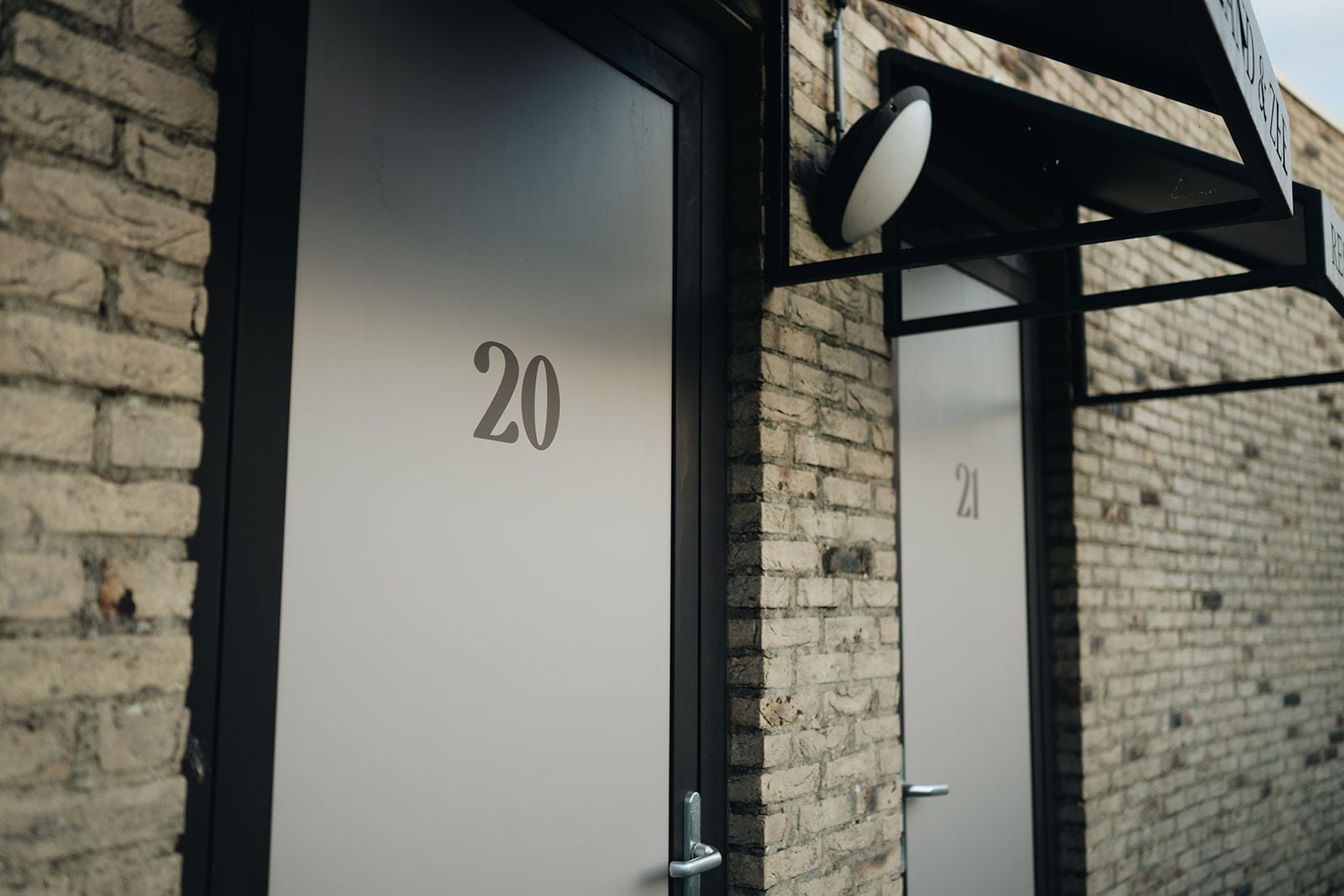 A building entrance with a brick wall and a door labeled '20'.