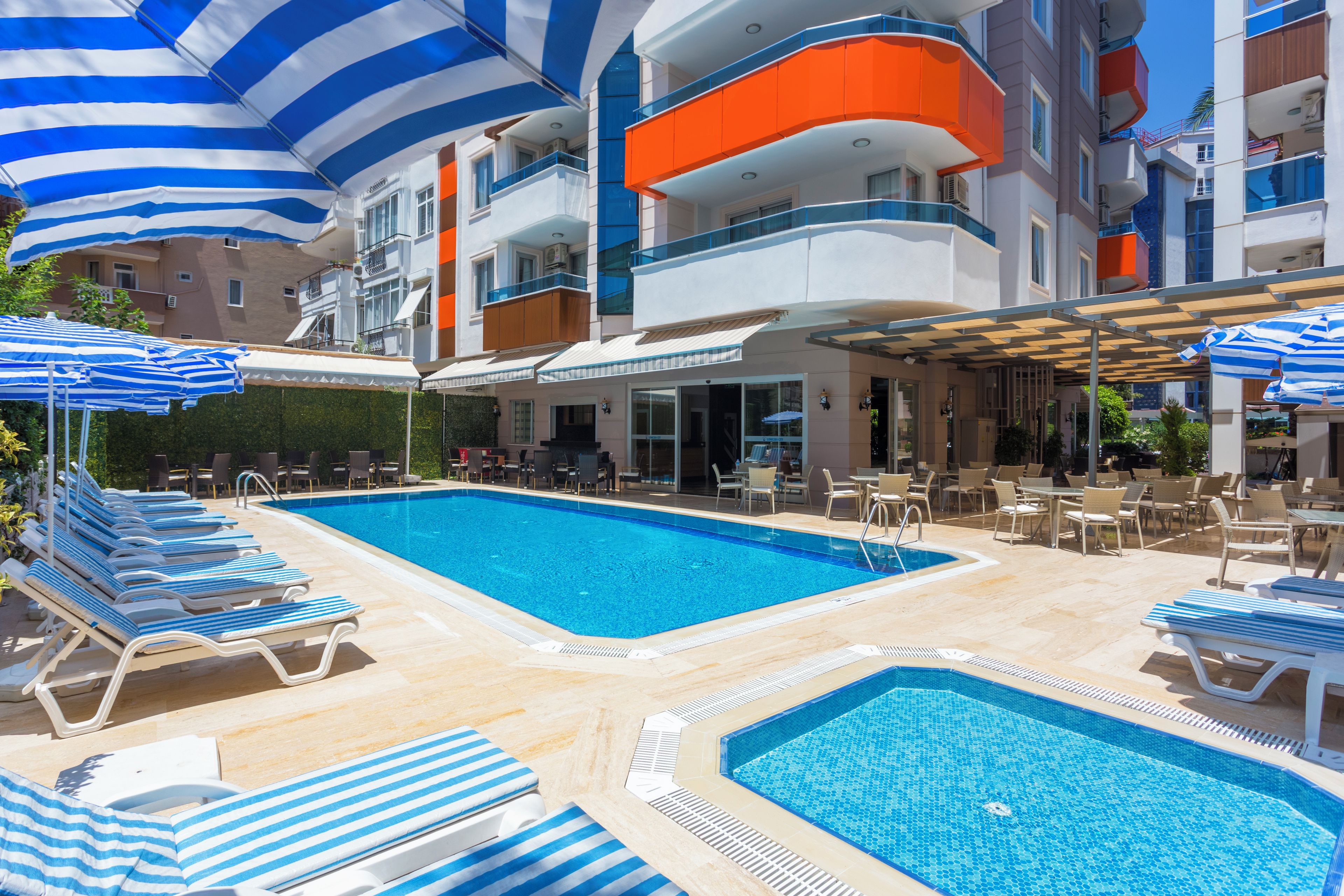 Een zwembadgedeelte van een hotel met meerdere zwembaden, ligbedden en parasols.