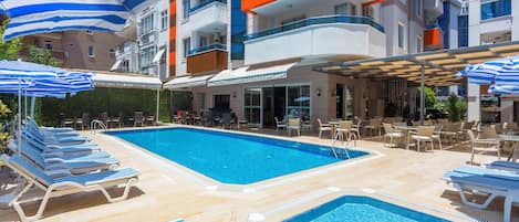 A hotel pool area with multiple pools, lounge chairs, and umbrellas.