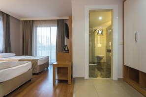 A hotel room with two beds, a wooden chair, a television, and a bathroom visible through an open door. - Lonicera City Hote (Alanya)