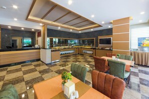 A modern hotel lobby with a checkered floor, a reception desk, a buffet area, and seating arrangements. - Lonicera City Hote (Alanya)