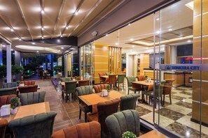 Un restaurante moderno con piso a cuadros, sillas tapizadas en verde y marrón, y un letrero que dice "LONICERA CITY".