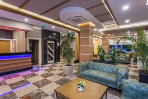 A lobby with a reception desk, seating area, and potted plants. - Lonicera City Hote (Alanya)