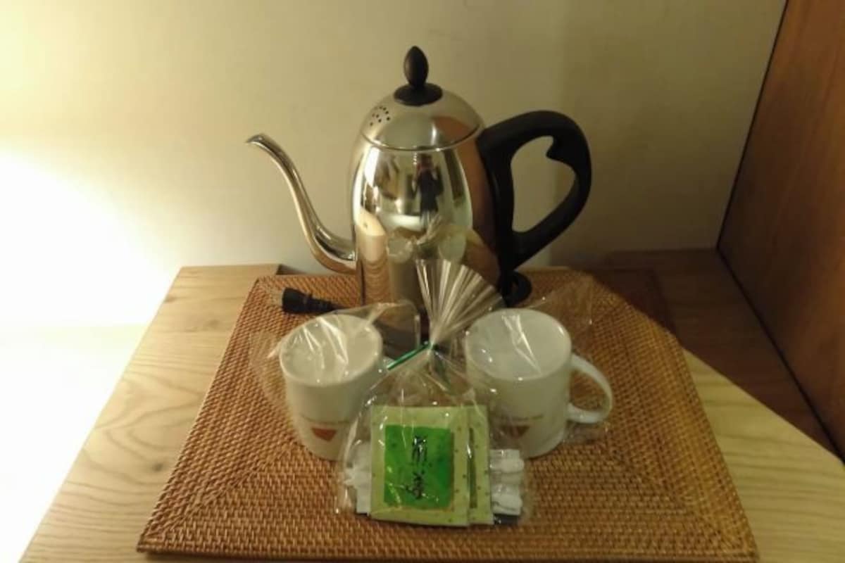 A tea set on a woven mat, including a teapot, cups, and a packet of tea.