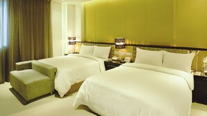 A hotel room with two beds, a small sofa, a nightstand with lamps, and a large window with curtains. - Hsiangkelira Hotel (Kaohsiung)