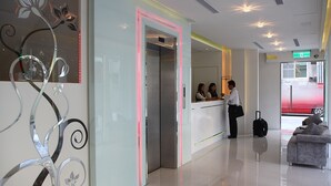A reception area with a modern design, including a glass partition with decorative metalwork, a reception desk, and a waiting area with a sofa. - Hsiangkelira Hotel (Kaohsiung)