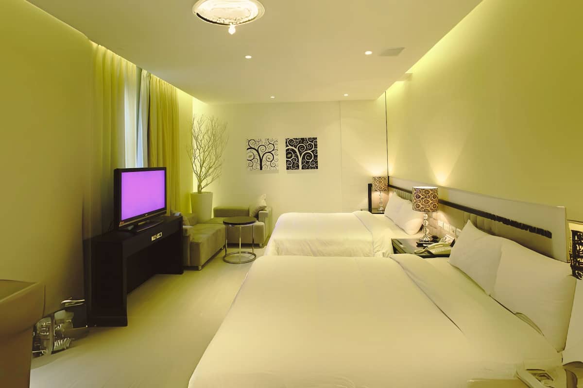 A modern hotel room with a large bed, a television, a small table, and a nightstand.