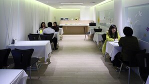 A conference room with tables and chairs, a reception desk, and a wall with floral decorations. - Hsiangkelira Hotel (Kaohsiung)