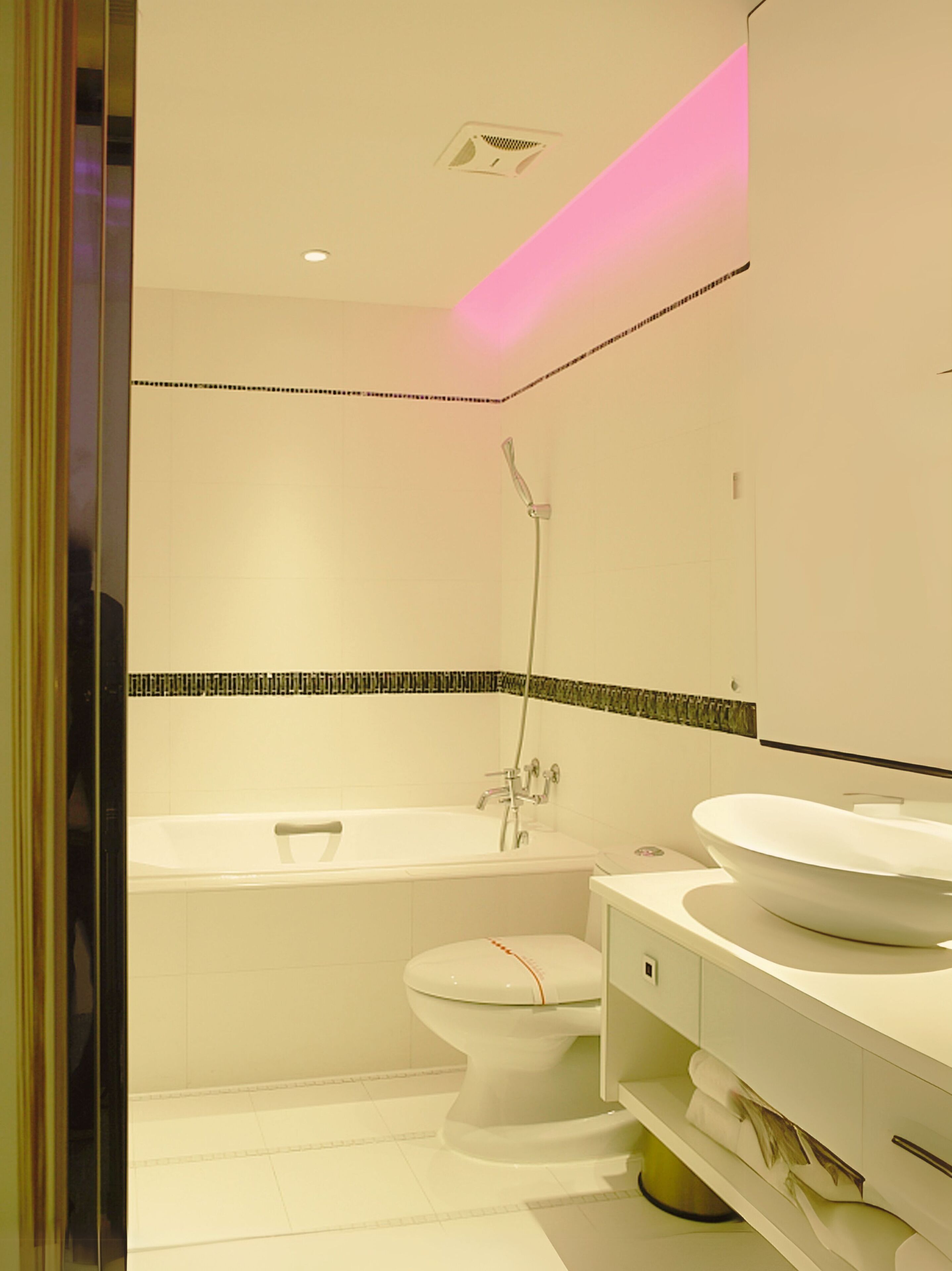 Un baño moderno con bañera, inodoro y un espejo grande.