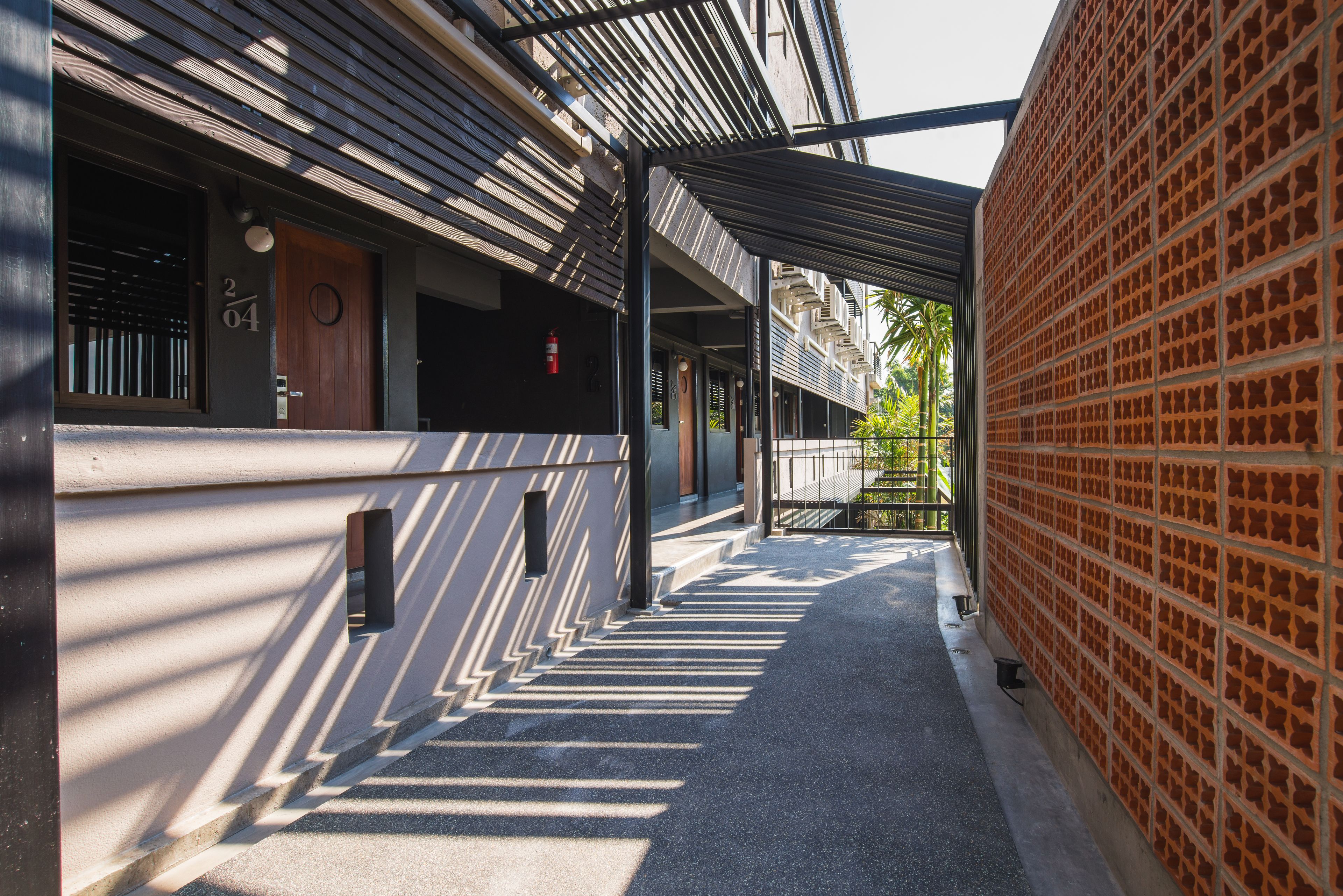 A covered walkway with a brick wall on one side and a building entrance on the other.