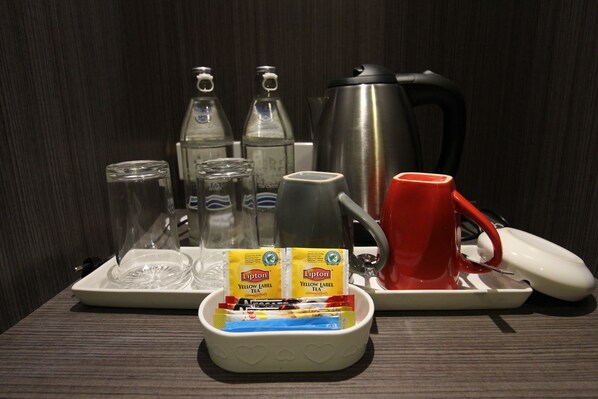 A tray with a red mug, a white mug, two Lipton tea packets, a glass carafe, and a stainless steel coffee pot. - The Sila Sriracha (Si Racha)