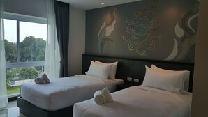 A hotel room with two beds, a large window with curtains, and a decorative wall mural. - The Sila Sriracha (Si Racha)