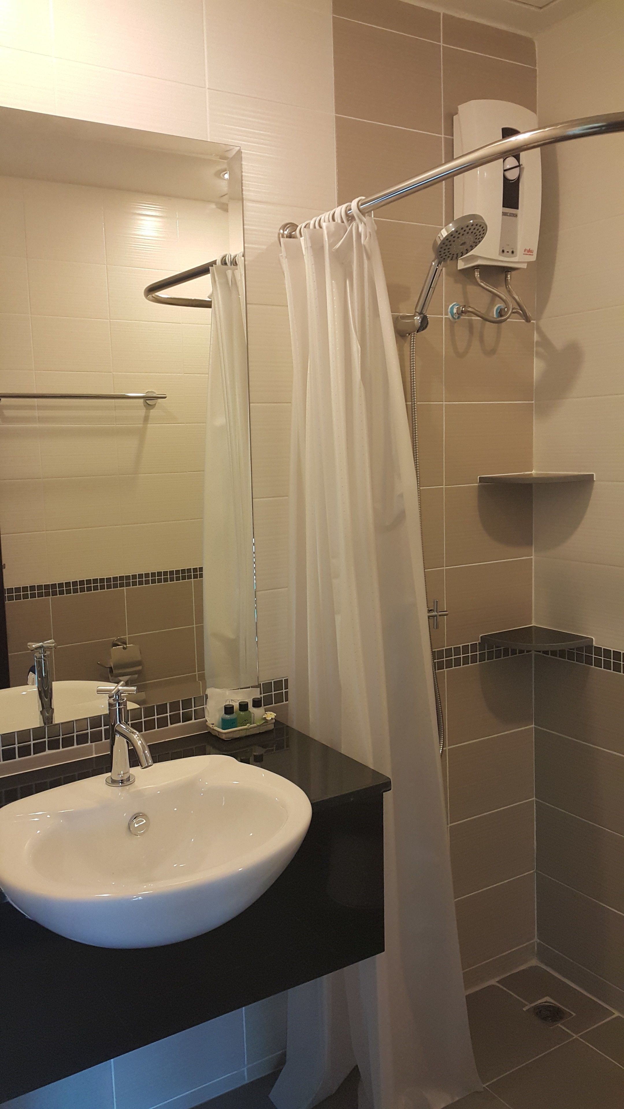 Ein Badezimmer mit Waschbecken, Spiegel, Dusche mit Glastür und Handtuchhalter.