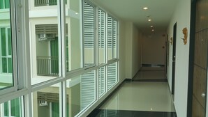 A corridor with large windows, a polished floor, and a wooden door. - The Sila Sriracha (Si Racha)