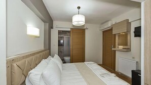 A hotel room with a bed, a bedside table, a wardrobe, and a shower area. - Metrolux Hotel (Istanbul)