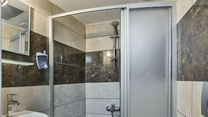 A modern bathroom with a shower enclosure, a sink, and a toilet. - Metrolux Hotel (Istanbul)