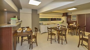 A hotel dining area with multiple tables and chairs, a buffet setup, and a kitchen in the background. - Metrolux Hotel (Istanbul)