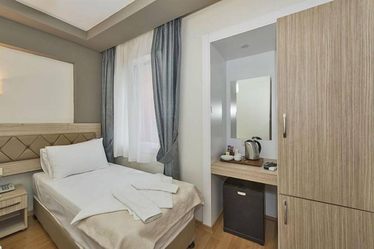 Una habitación de hotel con una cama, un escritorio, un espejo y un armario.