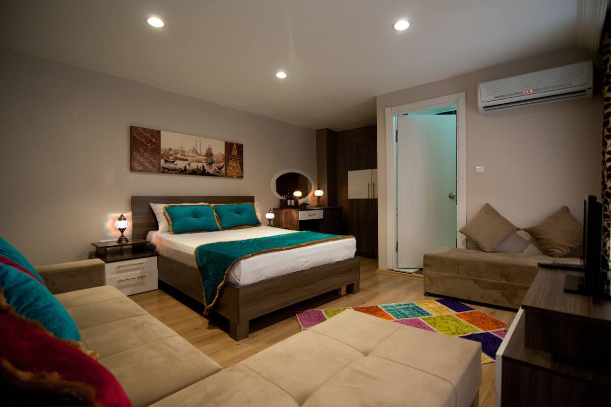 A bedroom with a bed, a nightstand, a dresser, a chair, and a door leading to another room.