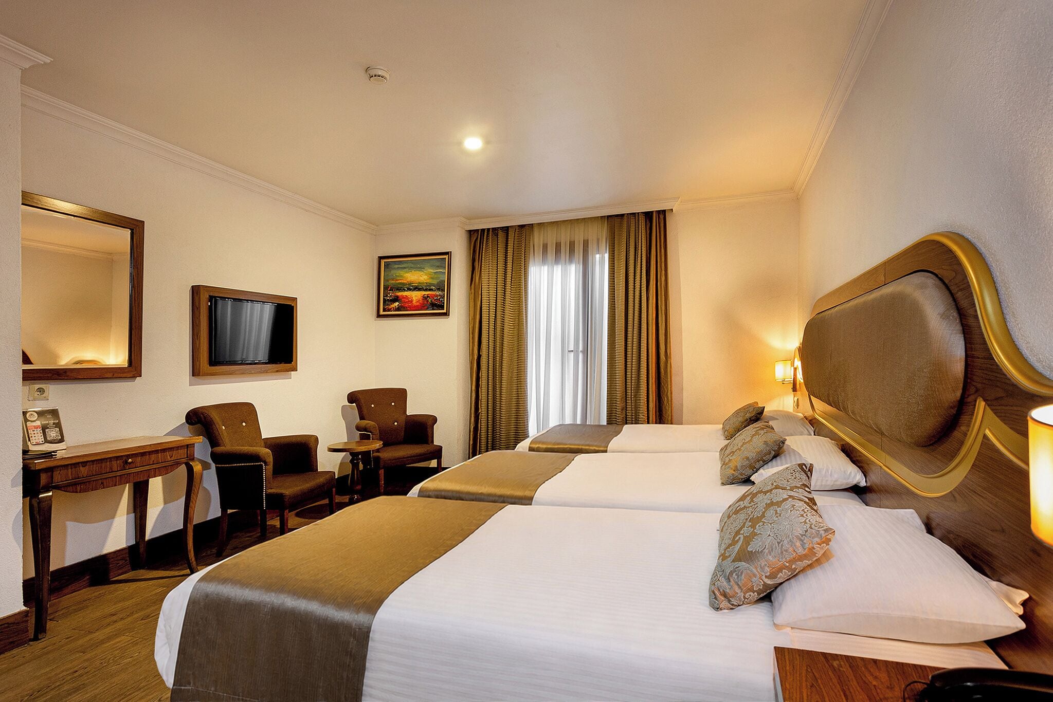 Una habitación de hotel con una cama grande, un escritorio con teléfono, un televisor y un cuadro en la pared.