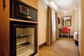 Une chambre d’hôtel équipée d’un minibar, d’un téléphone, d’un miroir et d’un plancher en bois.