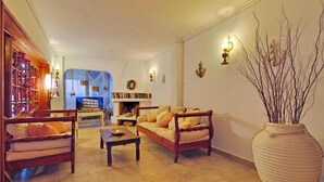 A living room with a sofa, armchairs, a coffee table, a fireplace, and a large vase. - Maistrali (Serifos)