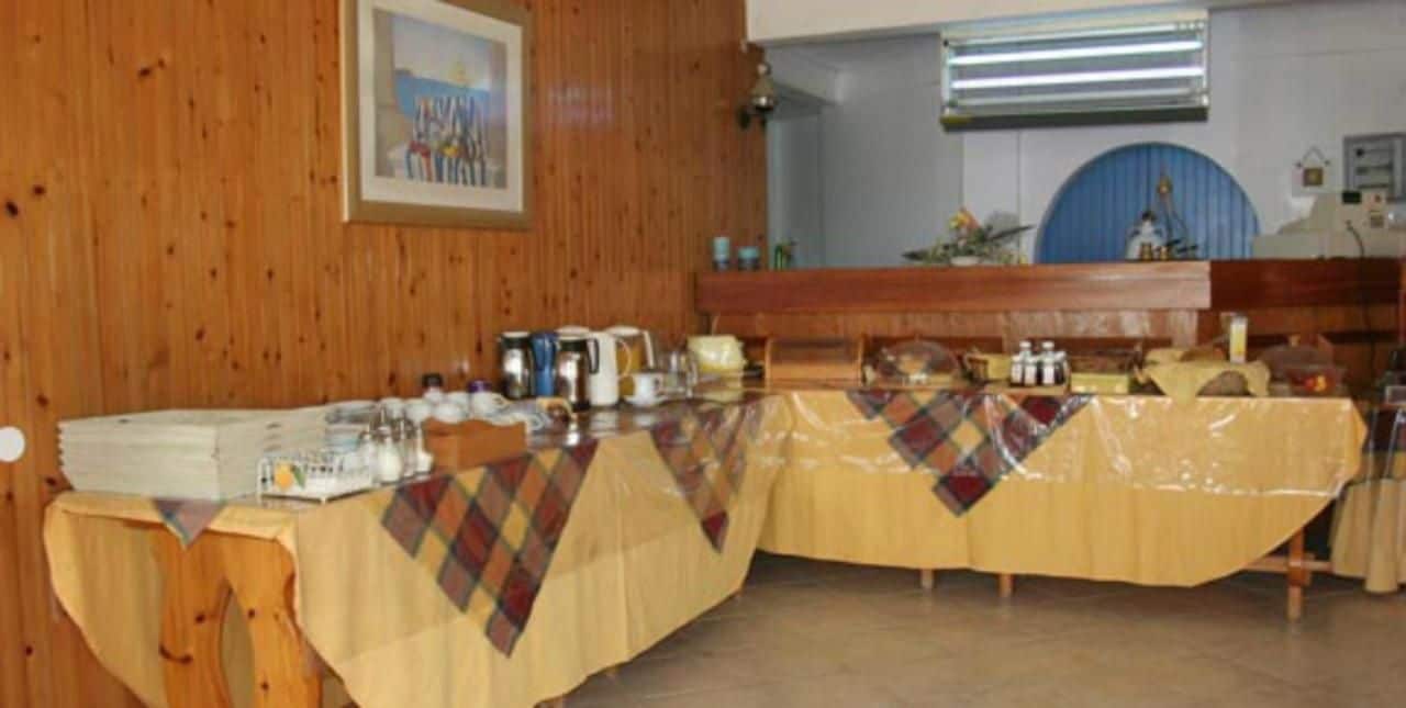 A long table with a plaid tablecloth, various dishes, and a blue wall with a framed picture.