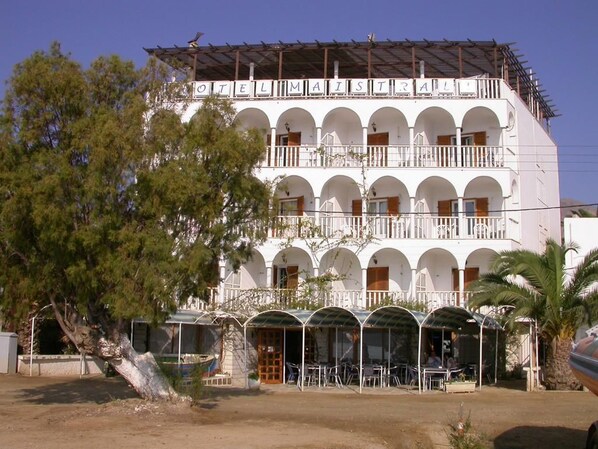 A multi-story building with balconies, outdoor seating, and a covered area. - Maistrali (Serifos)