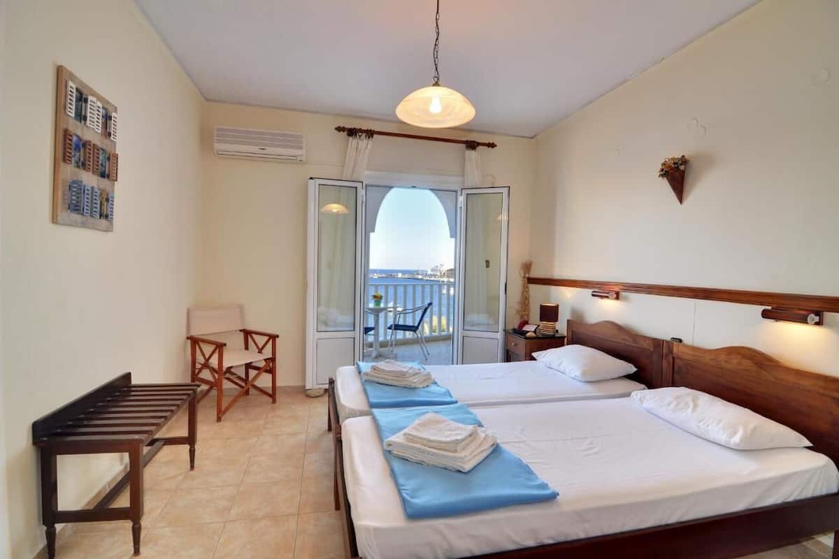 Une chambre d’hôtel avec deux lits, un bureau, une chaise et un balcon avec vue.